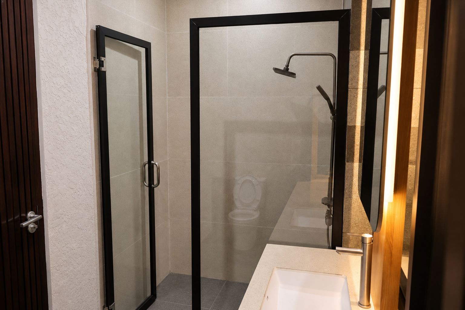 A bathroom with a glass-enclosed shower, a toilet, and a sink.