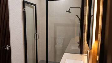 A bathroom with a glass-enclosed shower, a toilet, and a sink.