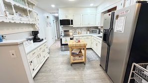 A modern kitchen with white cabinetry, stainless steel appliances, and a wooden table. - River Retreat dogs welcome amazing views & sunnroom (Hague)