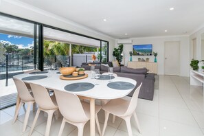 Ein modernes Wohnzimmer mit Essbereich, großen Fenstern und Blick ins Freie.
