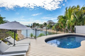 Ein Poolbereich mit Liegestühlen und Blick auf eine Stadtlandschaft.