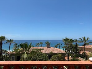Une propriété située sur la côte, offrant une vue sur l’océan, des palmiers et un bâtiment au toit rouge.
