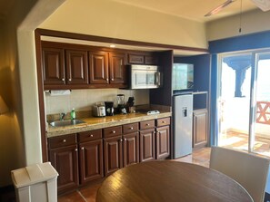 Una cucina con mobili in legno, un forno a microonde, un frigorifero, un lavello e un tavolo da pranzo.