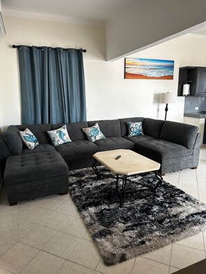 A living room with a sectional sofa, a small coffee table, and a fluffy rug. - Cabo Hideaway | Near Beach and Center + Parking. (Cabo San Lucas)