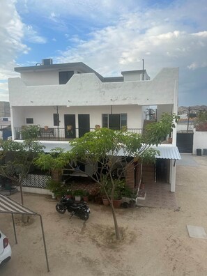 A modern two-story building with a flat roof, a covered patio area with potted plants, and a motorcycle parked in front. - Cabo Hideaway | Near Beach and Center + Parking. (Cabo San Lucas)