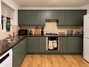A kitchen with green cabinets, a microwave, a stove, a sink, and a toaster. - Stylish  4BR Home | Perfect for Contractors (Bishop Auckland)