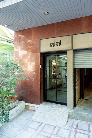 A building entrance with a glass door, a metal gate, and a small step leading up to the door. - T room Silom4 (Bangkok)