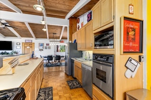 A modern kitchen with wooden cabinets, stainless steel appliances, and a dining area with a table and chairs. - RidgeView | Hot Tub & Sauna | Wraparound Decks | Mountain Views | Idyllwild (Idyllwild)