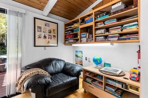A room with a black leather sofa, wooden bookshelves filled with books, a framed picture on the wall, and a globe on a side table. - RidgeView | Hot Tub & Sauna | Wraparound Decks | Mountain Views | Idyllwild (Idyllwild)