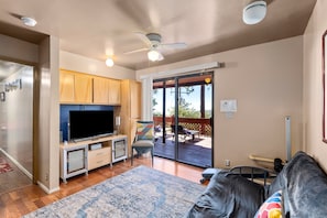 A living room with a flat-screen TV, wooden cabinets, a ceiling fan, and a view of the outdoors. - RidgeView | Hot Tub & Sauna | Wraparound Decks | Mountain Views | Idyllwild (Idyllwild)