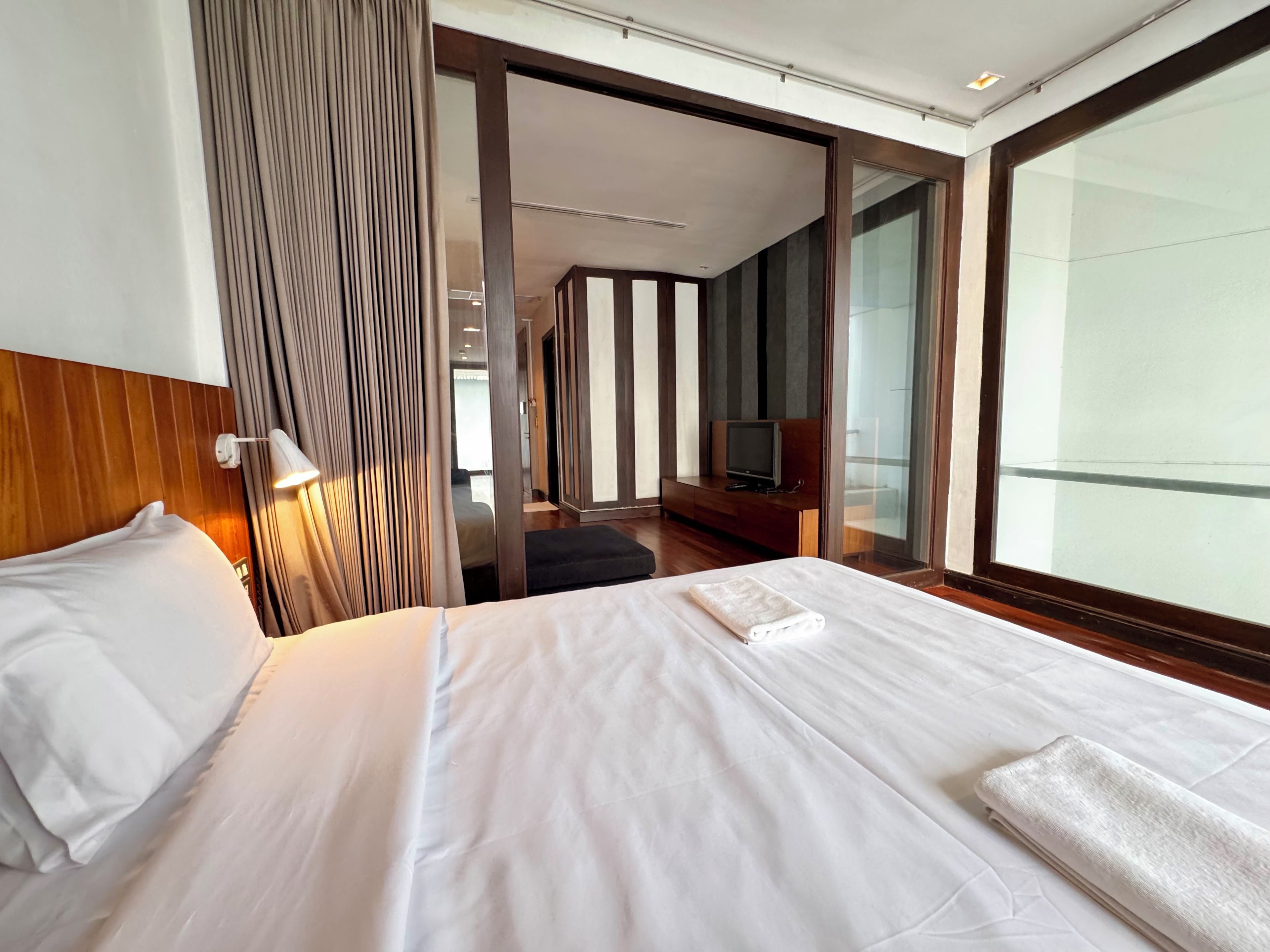 Ett hotellrum med en stor säng, en tv och utsikt genom en glasdörr.