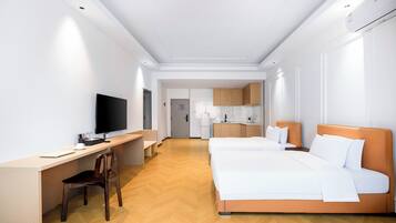 A hotel room with a bed, desk, chair, television, and a kitchenette.