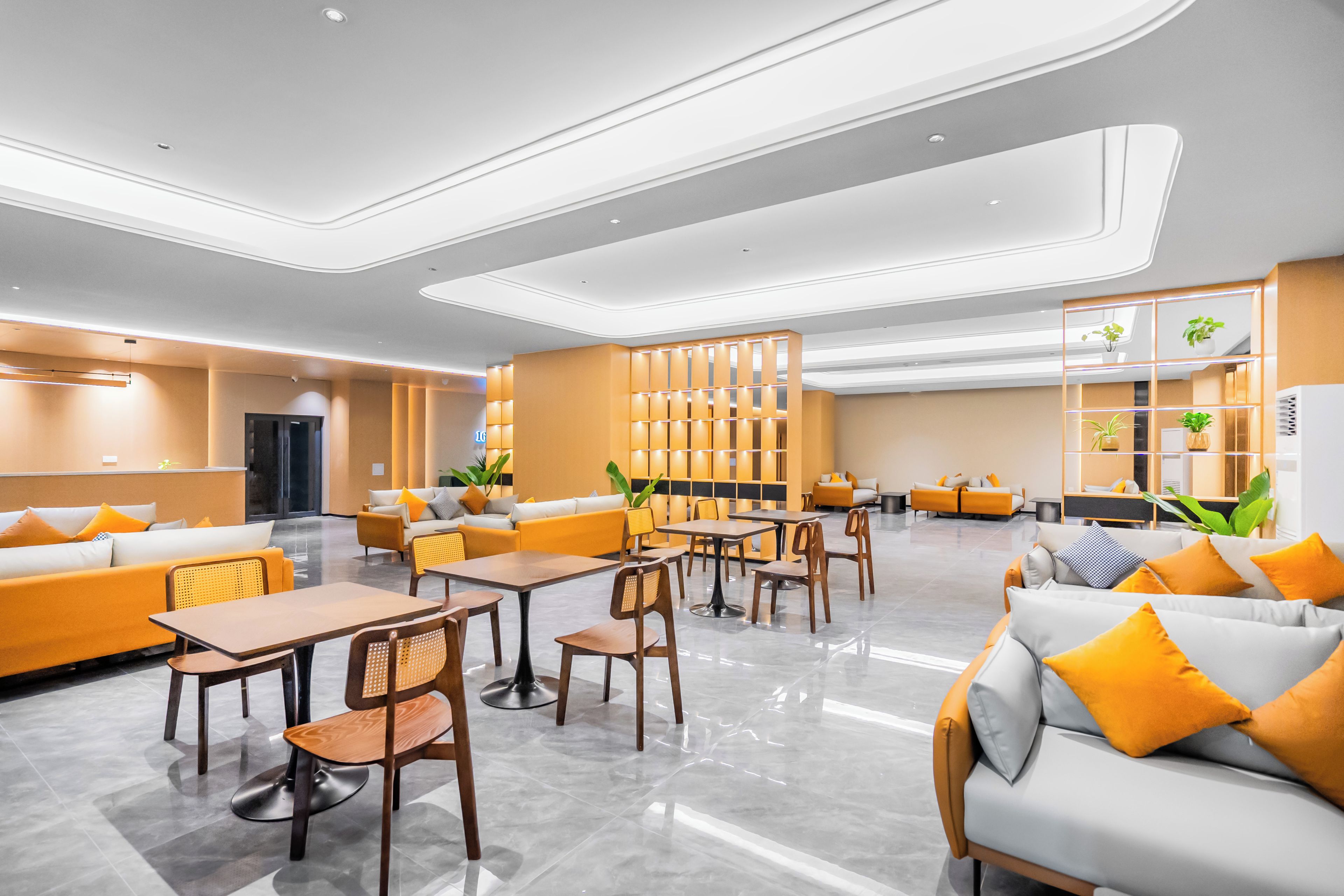 En moderne hotellobby med siddepladser, borde og en receptionsdisk.
