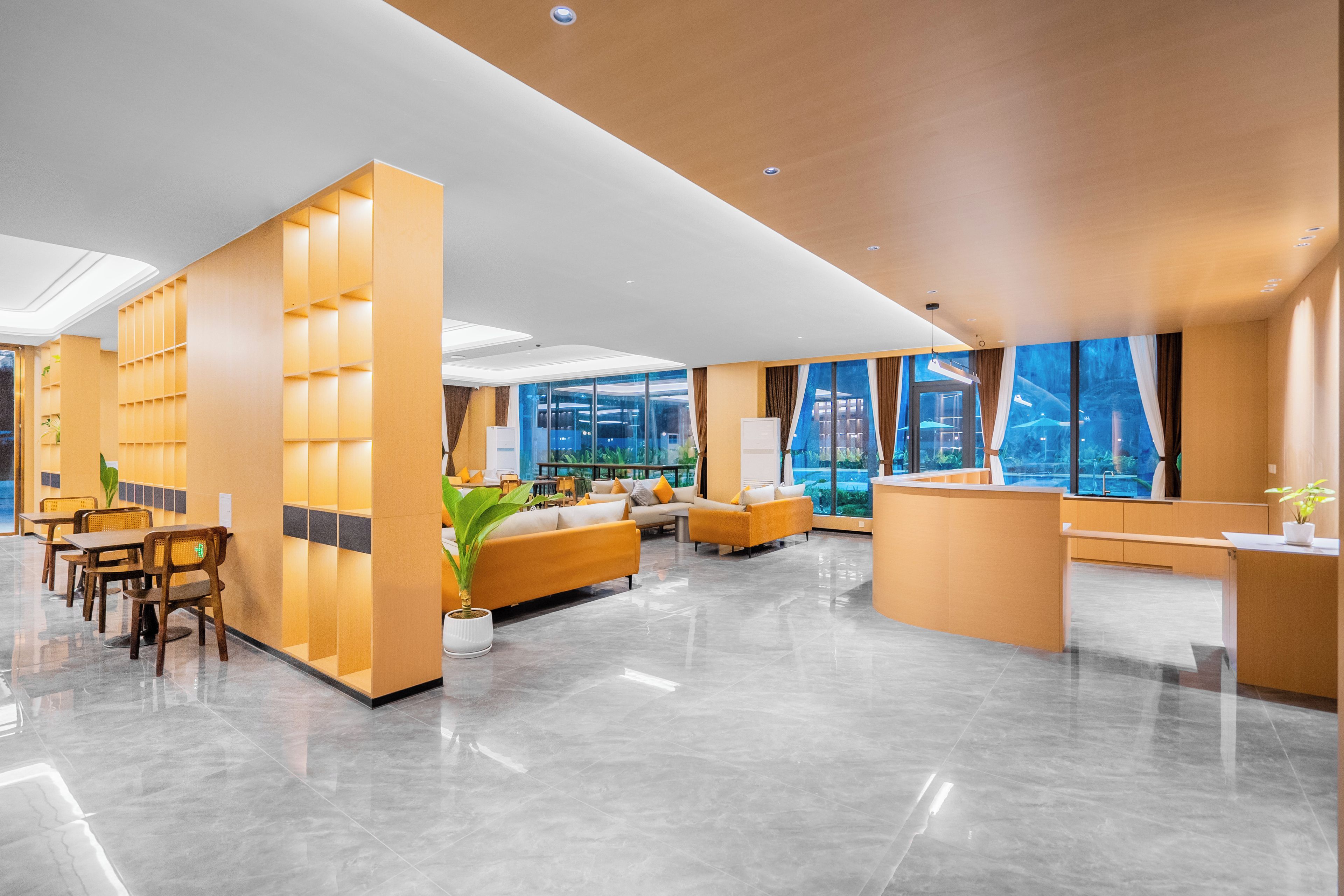 En moderne lobby med receptionsdisk, siddeområde og store vinduer med udsigt over bybilledet.