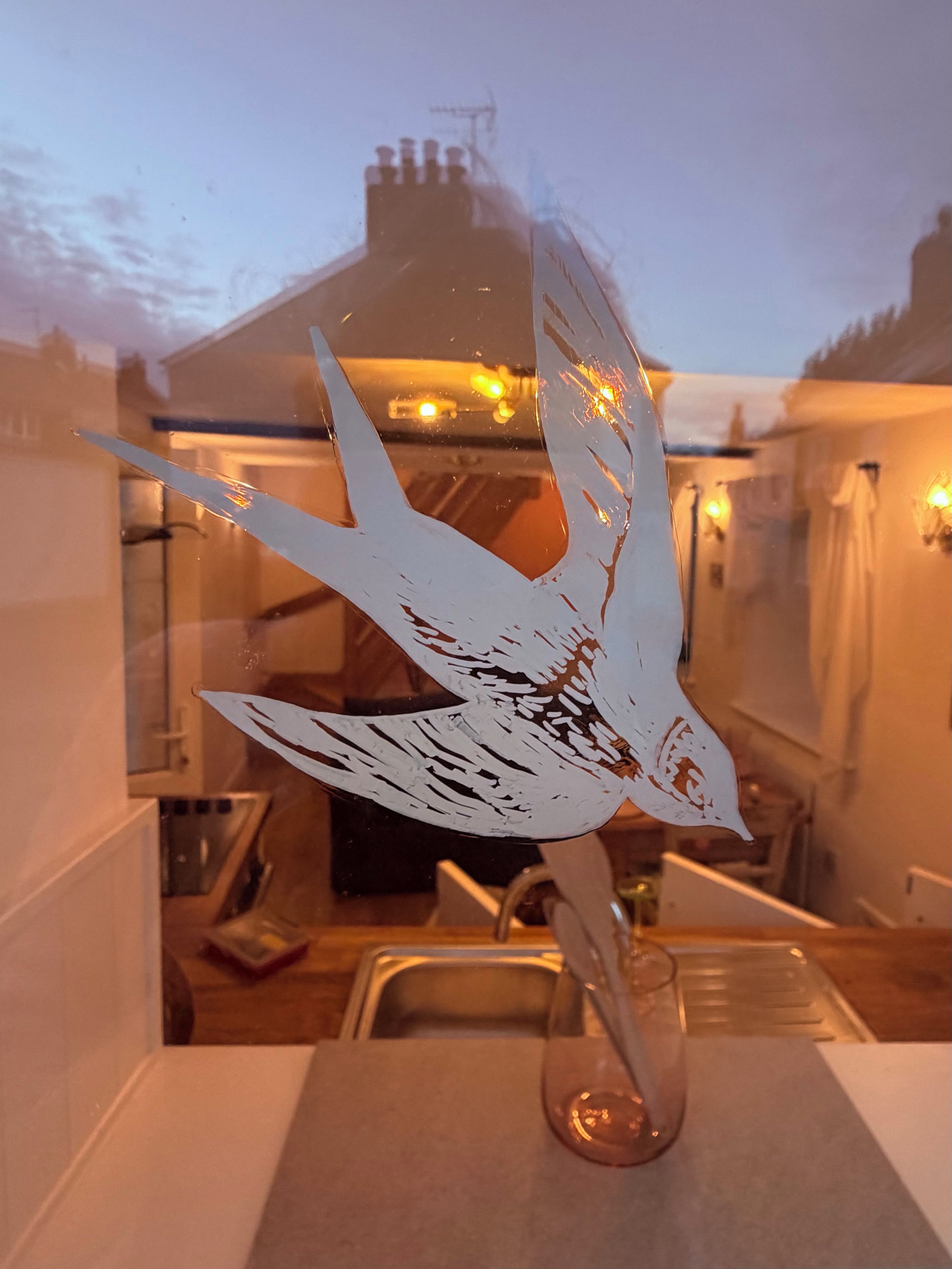 Una cocina con un lavamanos, un florero de vidrio y una escultura decorativa de un pájaro.