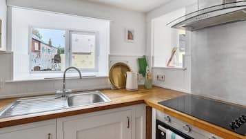 A modern kitchen with a stainless steel sink, a black stove, and a window with a view of a building.