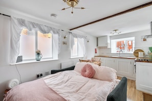 A bedroom with a bed, a window with curtains, a bedside table with a lamp, and a view of the outside.
