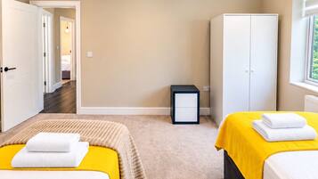 Une chambre d’hôtel avec deux lits, une armoire, une table de chevet et une fenêtre.