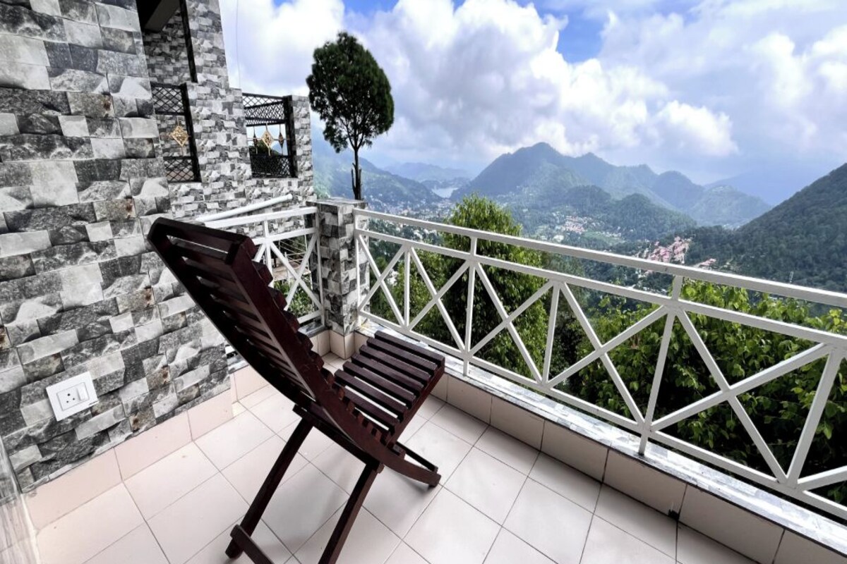 A balcony with a stone wall, a wooden bench, and a view of mountains.