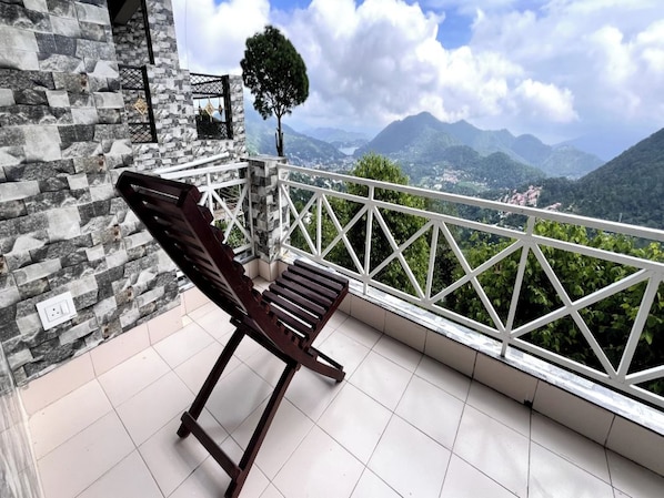 A balcony with a stone wall, a wooden bench, and a view of mountains.