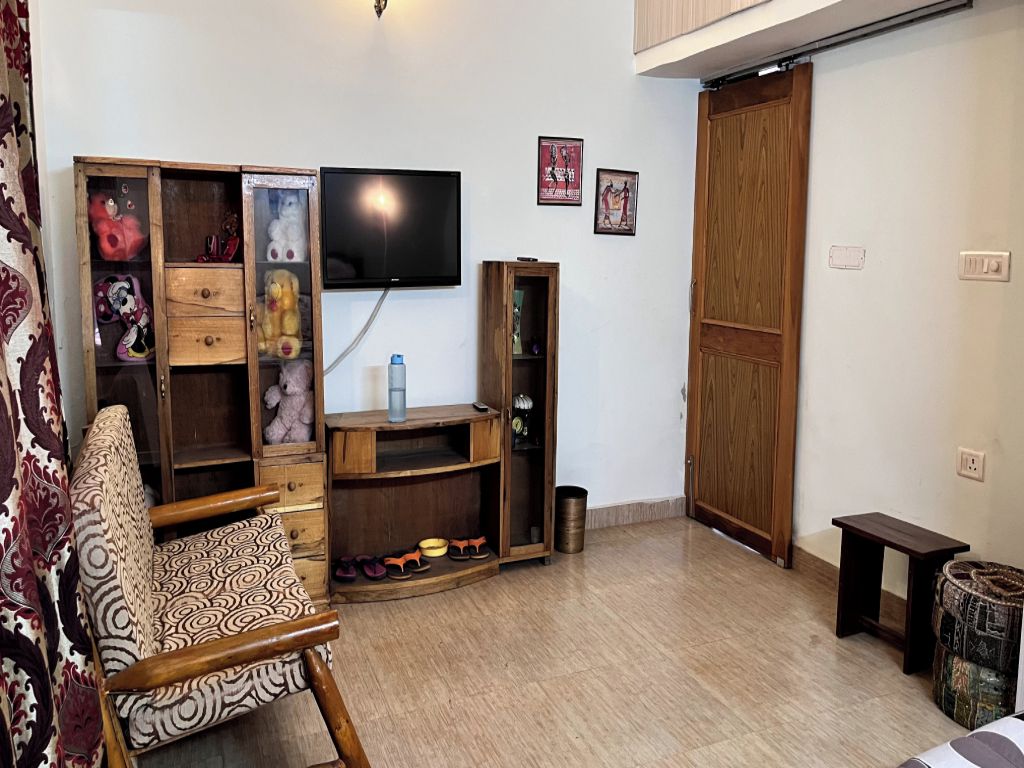 A living room with a television, wooden furniture, and a sliding door.