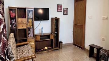 A living room with a television, wooden furniture, and a sliding door.