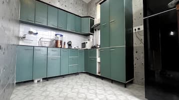 Una cocina con armarios color aguamarina, un microondas y un refrigerador.