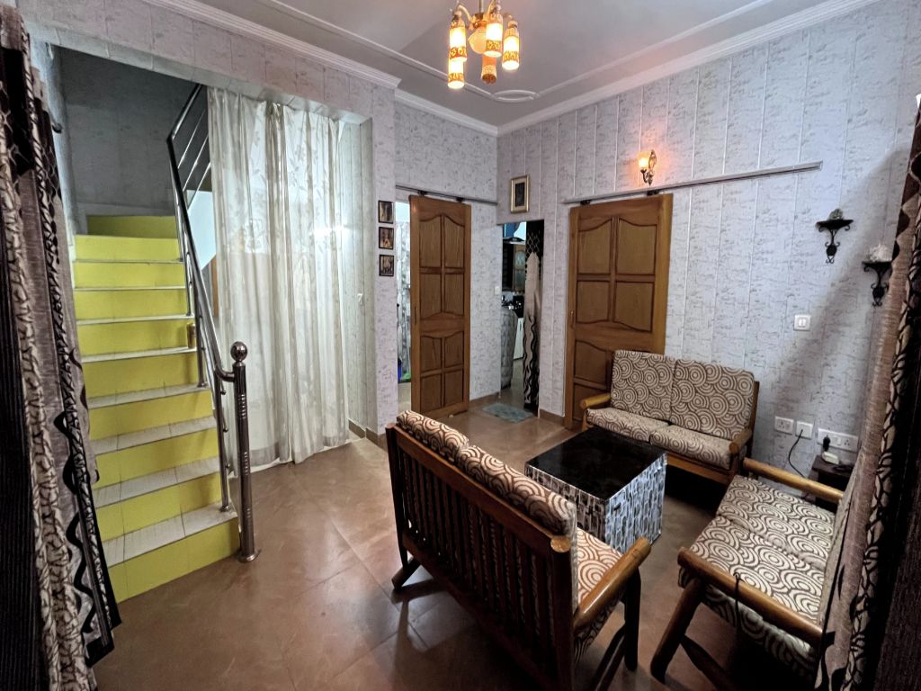A living room with a sofa, a coffee table, and a staircase with yellow steps.