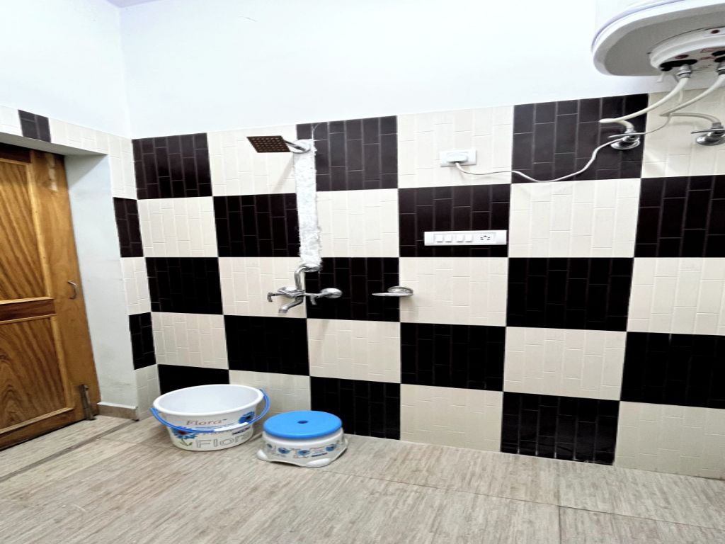 Un baño con baldosas a cuadros blancos y negros, una puerta de madera y un lavabo blanco con tapa azul.
