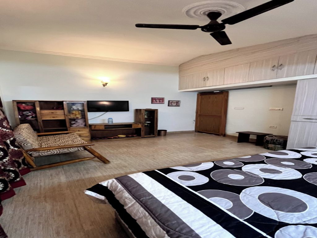 A bedroom with a bed, a ceiling fan, a television, and a wardrobe.