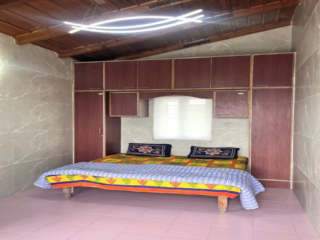 Een slaapkamer met een bed, houten hoofdbord en een raam.