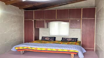 Een slaapkamer met een bed, houten hoofdbord en een raam.