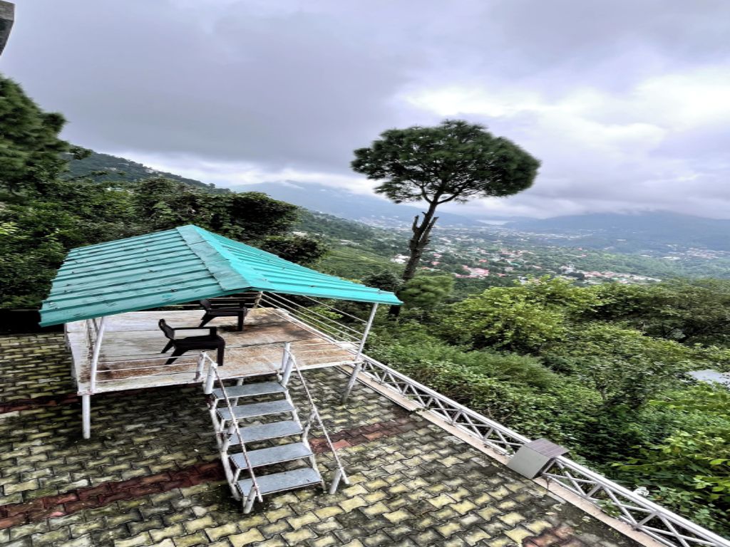Una terraza en la azotea con techo azul, una escalera de metal y vistas a un paisaje montañoso.