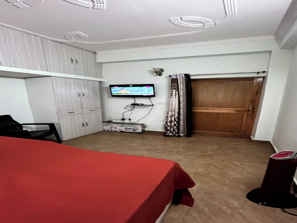 Une chambre avec un lit, une télévision, une armoire et un rideau.