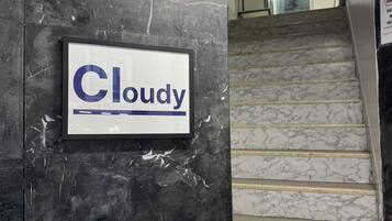Una escalera con un letrero que dice 'Cloudy' en una pared de mármol oscuro.