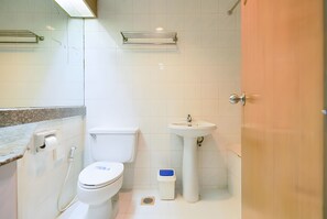 Un baño con inodoro, lavamanos y zona de ducha.