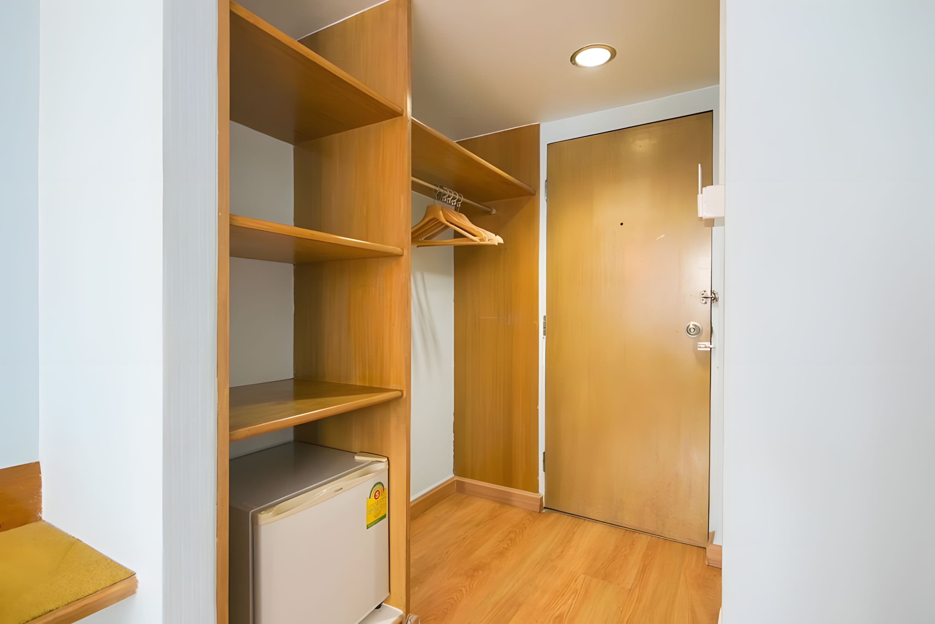 Un vestidor con estantes de madera, una barra para colgar ropa y una puerta con cerradura.