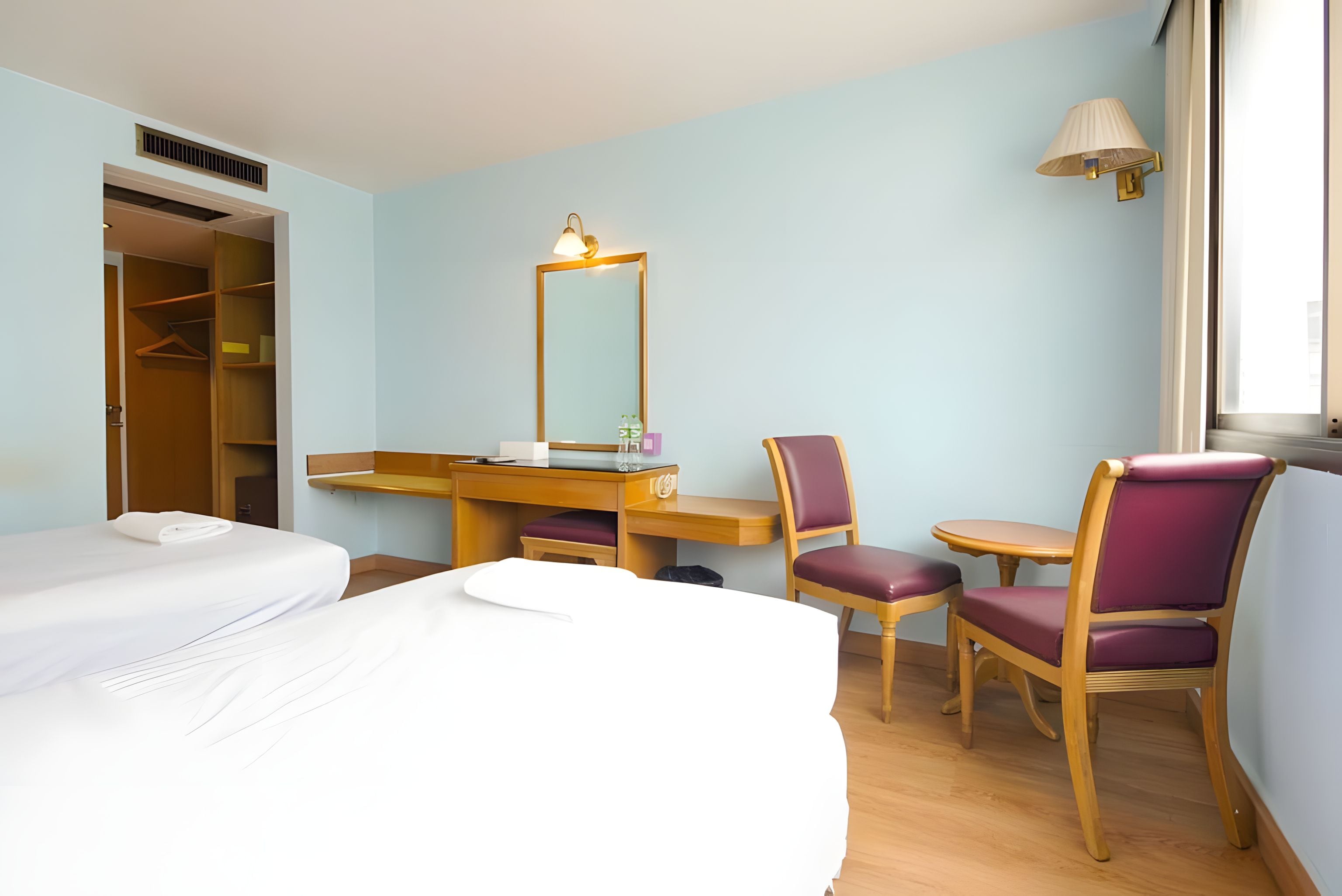 Una habitación de hotel con cama, escritorio, silla, espejo y ventana.