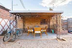 An outdoor patio with a wooden table and chairs, a bicycle, and a brick wall. - West Highlands- walk to Tennyson and Highlands Square (Denver)