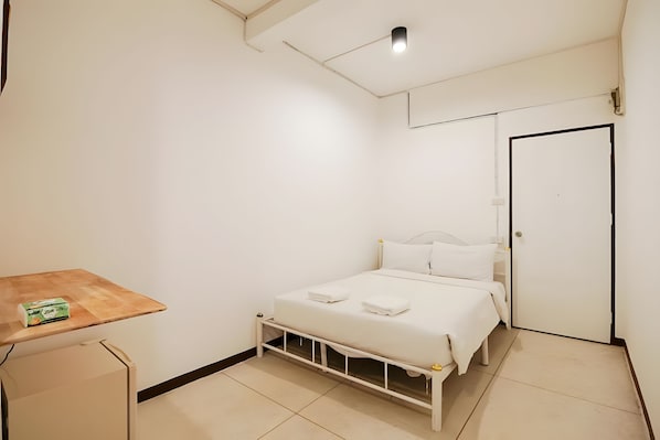 A bedroom with a bed, a small table, and a door. - A room Asiatique (Bang Kho Laem)