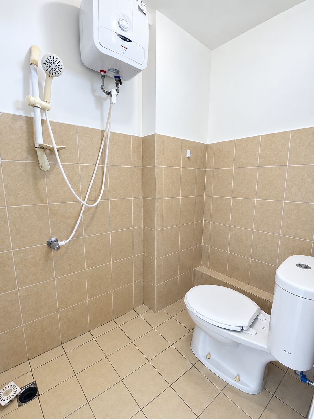 Un baño con inodoro, ducha y dispensador de papel higiénico de pared.