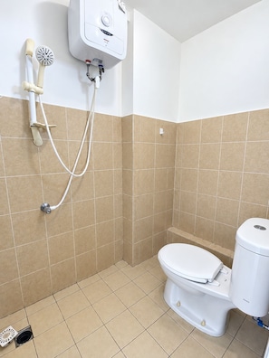 A bathroom with a toilet, a shower unit, and a wall-mounted toilet paper holder. - Golden inn Treepark city apartemen (Tangerang)