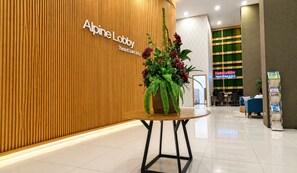 A reception area with a wooden wall, a reception desk, and a potted plant. - Golden inn Treepark city apartemen (Tangerang)