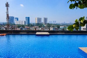 A swimming pool with a cityscape view, including high-rise buildings and a communication tower. - Golden inn Treepark city apartemen (Tangerang)
