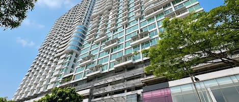 Un edificio a grattacielo con diversi piani, un'area di parcheggio con numerose auto e un cielo azzurro limpido.