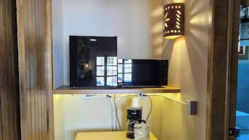Un pasillo estrecho con un mueble de madera, una cafetera e iluminación empotrada.