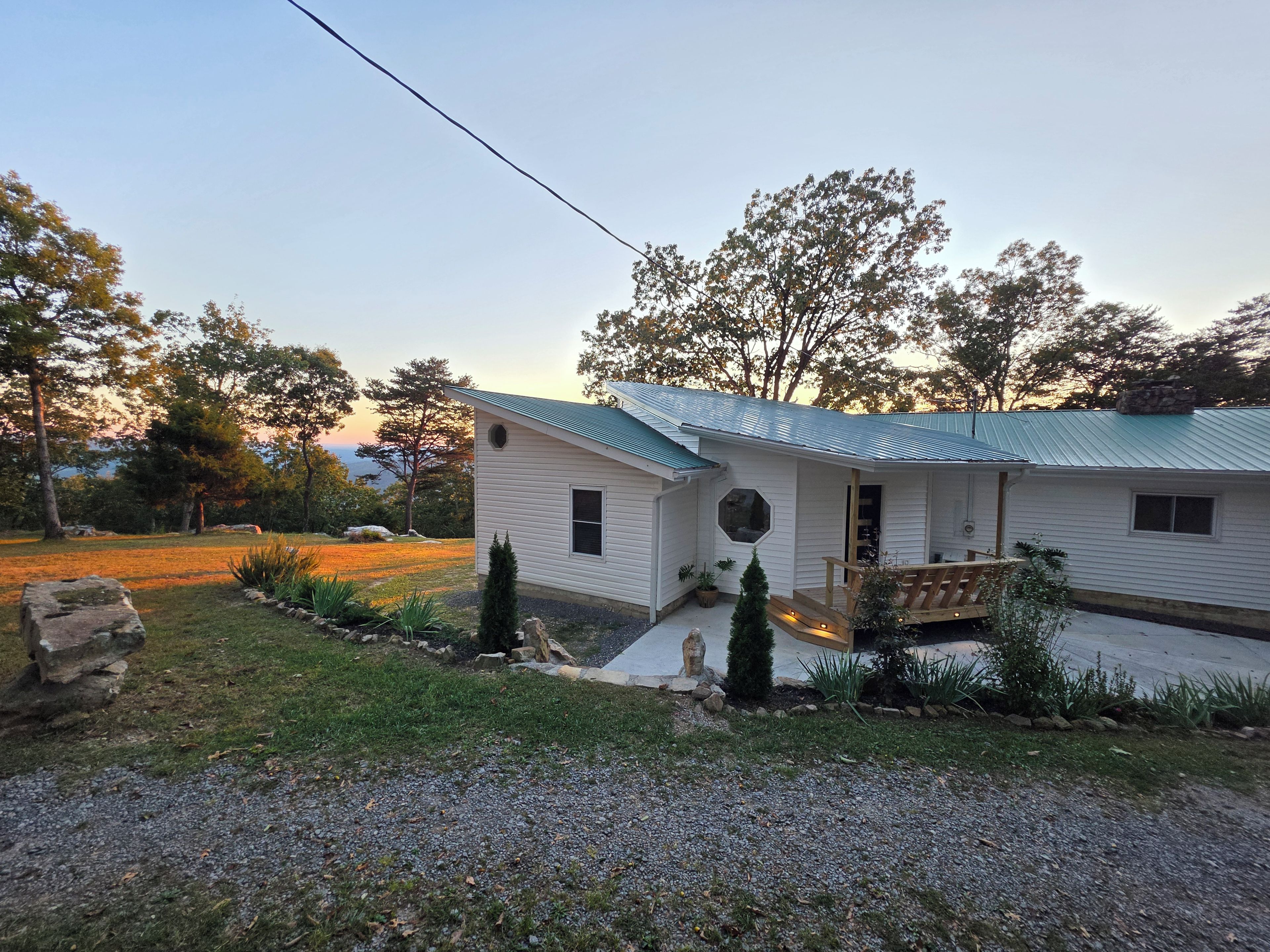 Une maison de plain-pied avec un toit végétalisé, un porche à l’avant et un petit jardin devant, agrémenté d’un muret en pierre et de plantes en pot.