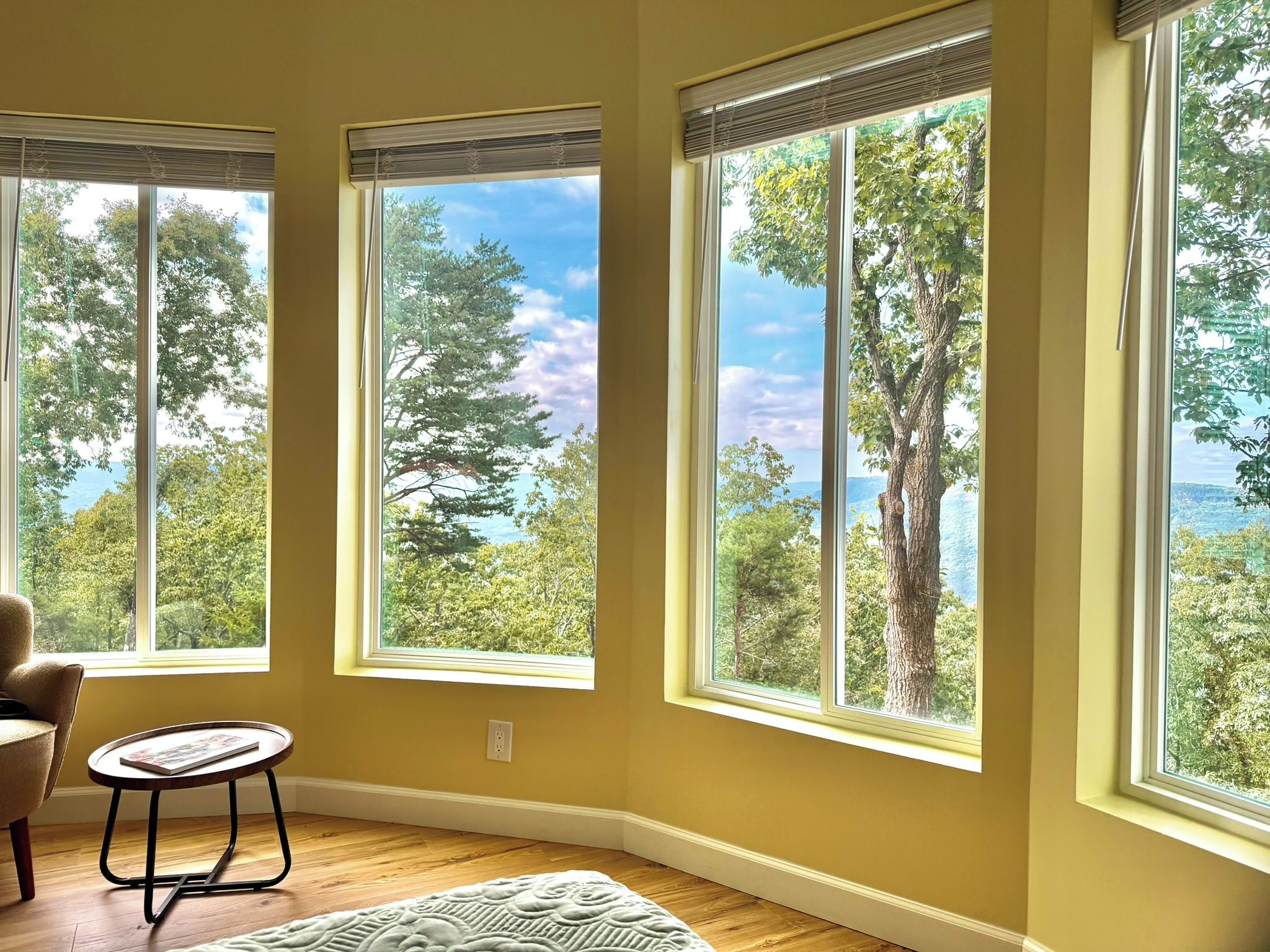 A room with large windows, a chair, and a small table.