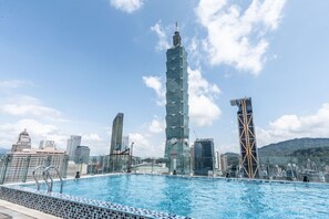 Piscina com paisagem urbana ao fundo, incluindo uma torre imponente.