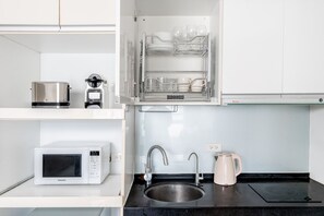 A modern kitchen with a microwave, coffee maker, sink, and a dish rack with glasses. - Blueground | Jingxin Village, pool, nr Taipei 101 (TPE-14) (Taipei)